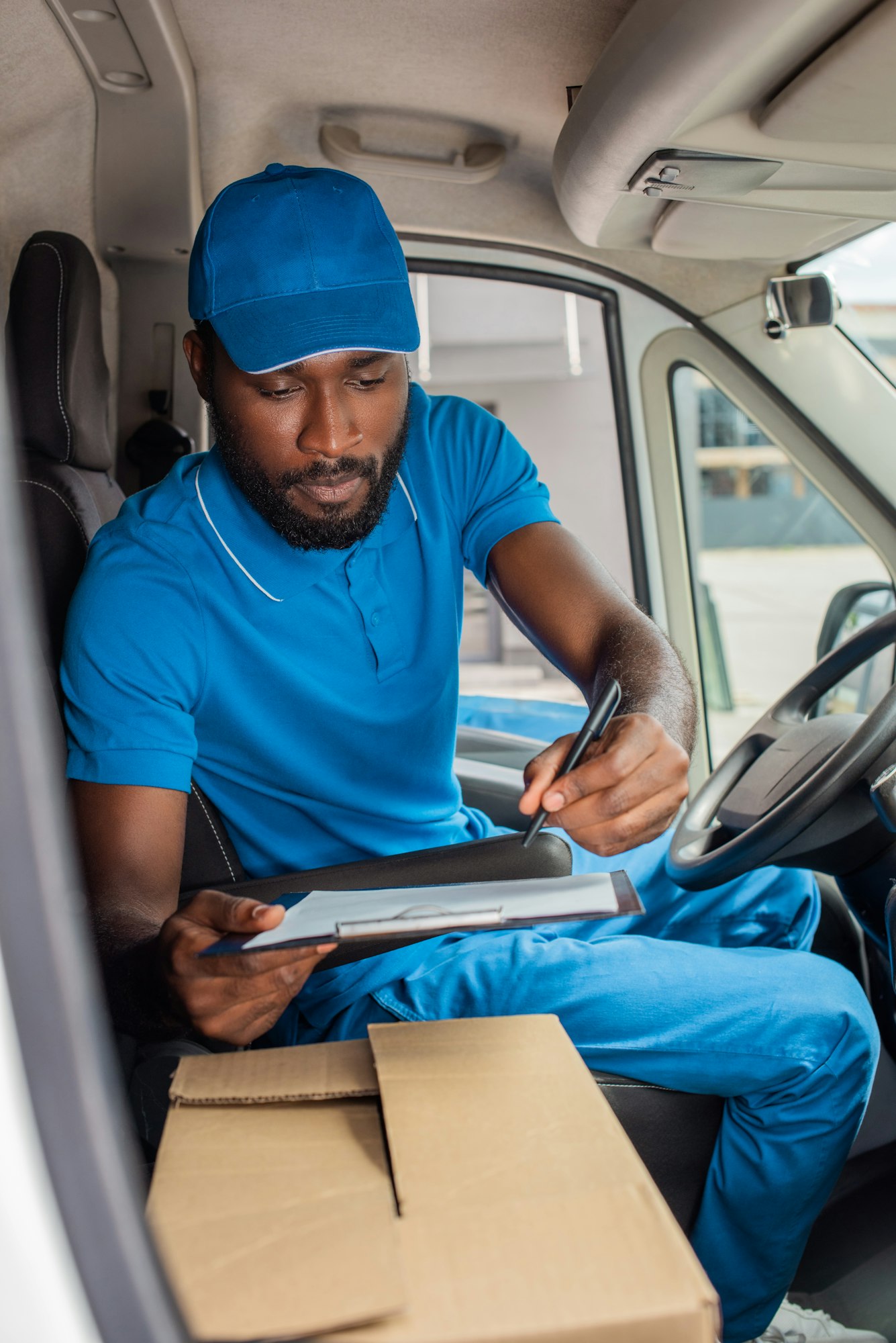 african american delivery man holding clipboard and pen in van