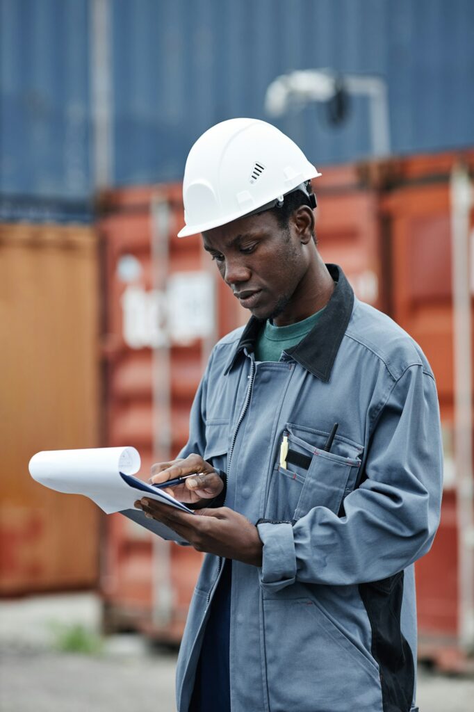 Black man wearing hardhat working at shipping docks